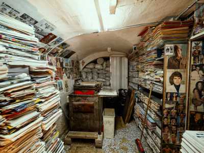 Sul pavimento invece svettano pile di libri e giornali...